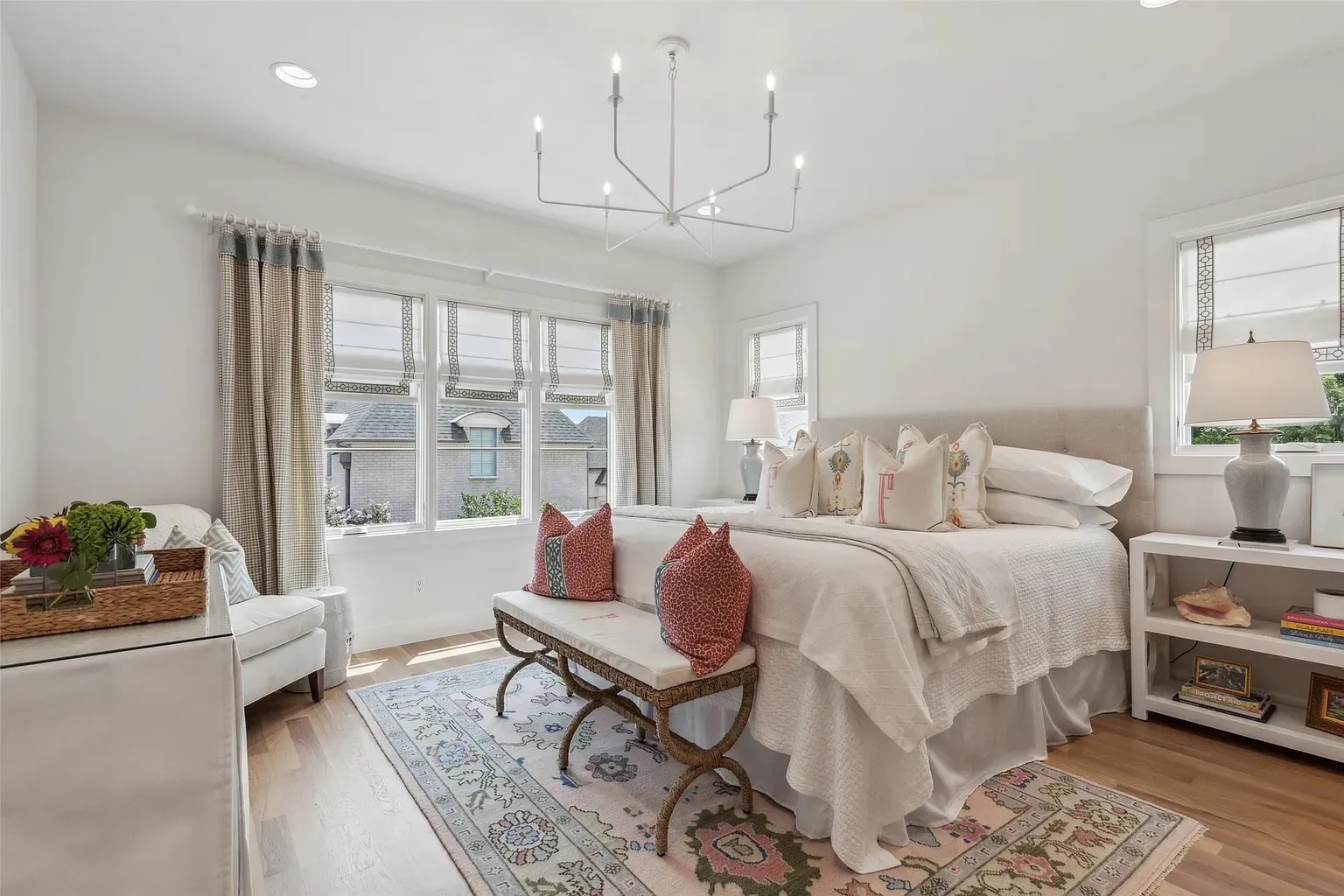 Bright and airy master bedroom with large windows, neutral color scheme, and modern chandelier